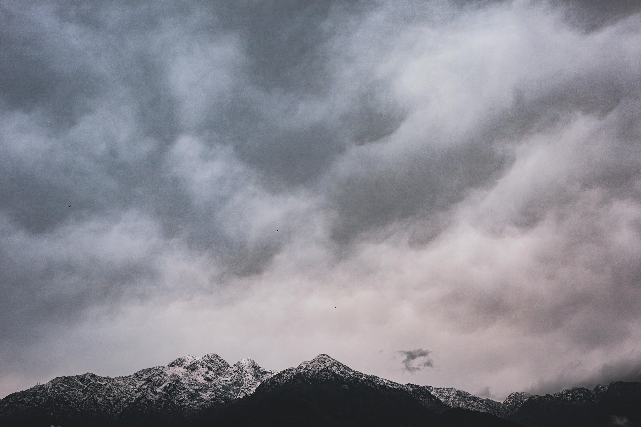 A captivating view of snow-covered mountains under a dramatic cloudy sky in Katra.