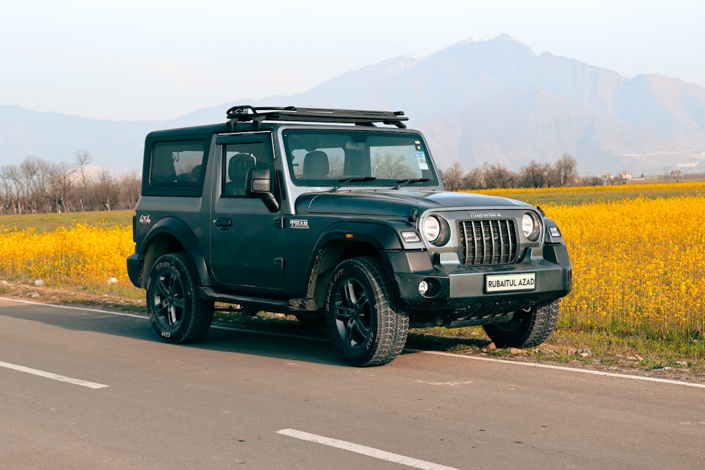 A rugged off-road vehicle parked by a vibrant field under a clear sky.