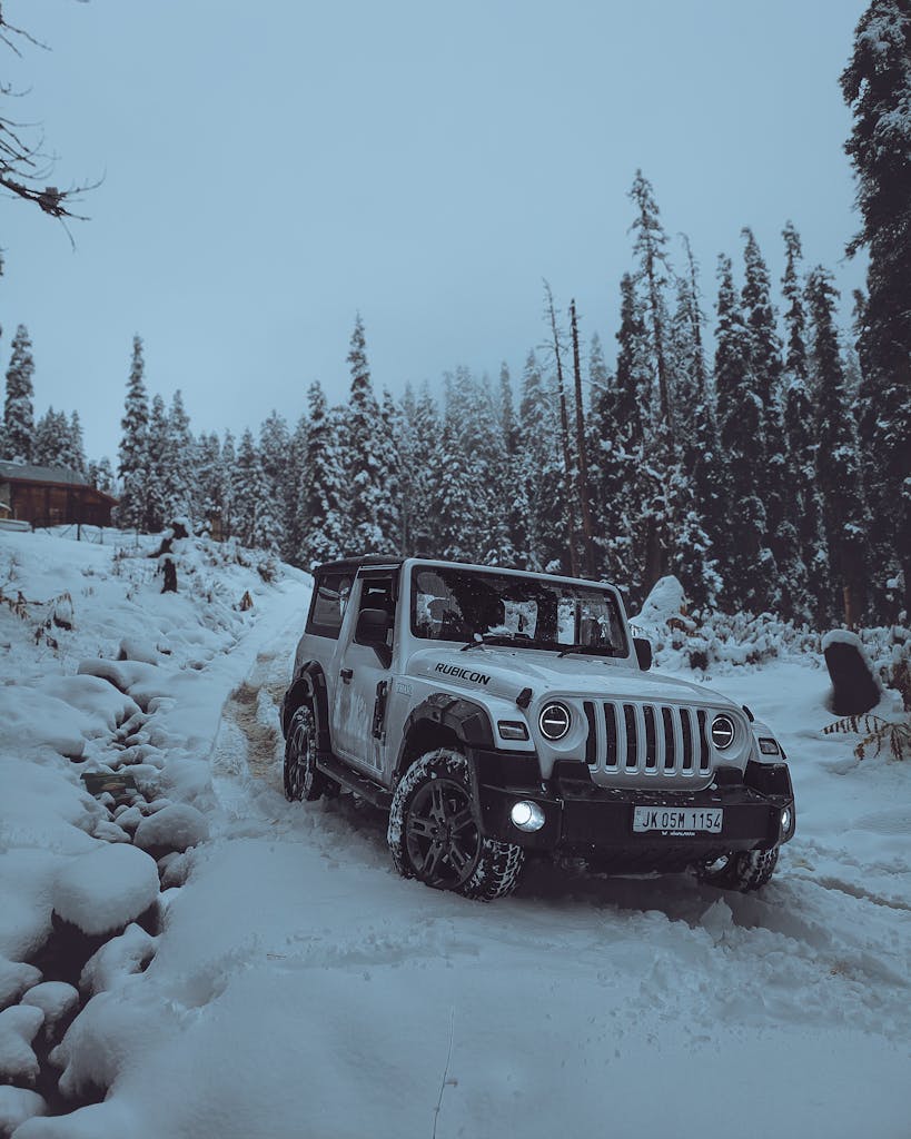 Four-wheel drive vehicle navigating snowy terrain in Gulmarg, Kashmir forest.