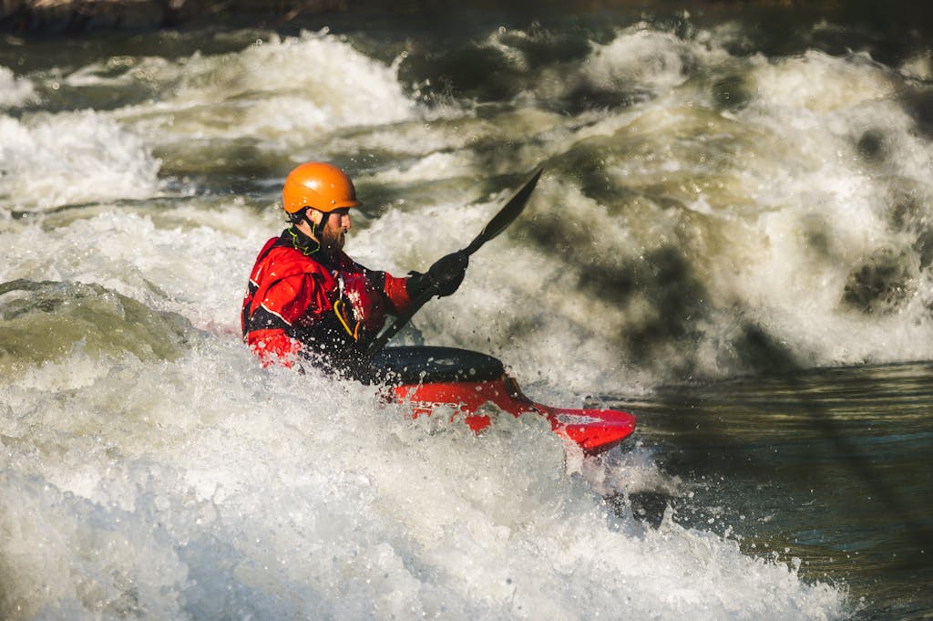 Man kayaking through whitewater rapids, showcasing adventure and outdoor excitement.
